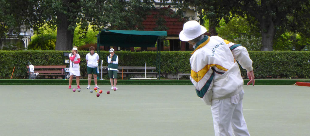 Lawn bowlers in pairs match watching a delivered bowl